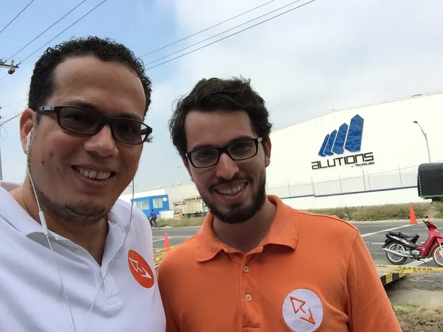 Carlos J. Carvajalino y Frank Jairo Ojeda frente a la planta de Alutions en Barranquilla, los dos con la camiseta de Interfaz Creativa